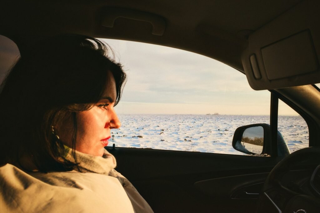 Woman looking out car window at snowy landscape