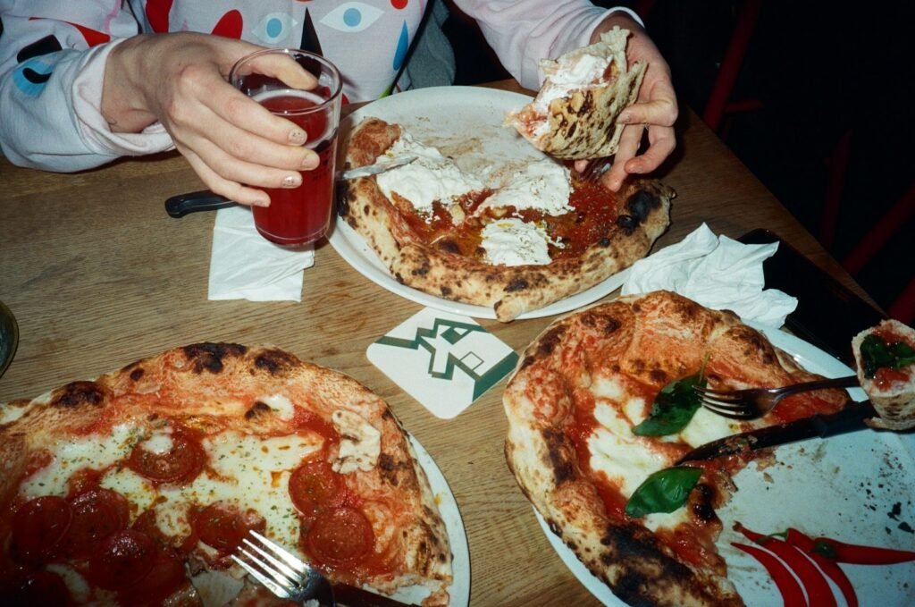 Three pizzas and a drink on a wooden table.